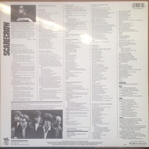 May include: Back cover of a vinyl record album for John Cougar Mellencamp's Scarecrow album. The album cover features a black and white photo of John Cougar Mellencamp with a band. The album cover includes the album title, artist name, and song titles. The album cover also includes the record label, PolyGram Records.
