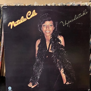 May include: A black and white vinyl record album cover featuring Natalie Cole. The album title is "Unpredictable" and the record label is Capitol Records.