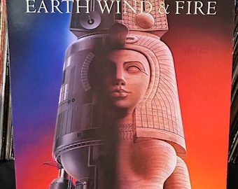 May include: A vintage vinyl record album cover featuring a futuristic illustration of a woman with a crown and a large metal structure. The album cover is titled "Earth Wind & Fire".