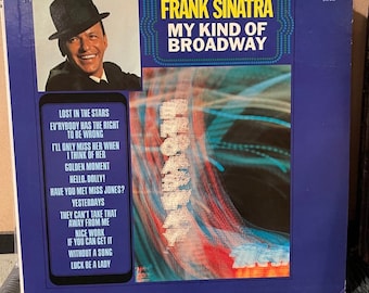 May include: A blue and white vinyl record album cover featuring Frank Sinatra. The album title is "My Kind of Broadway". The cover art features a blurry image of a stage with lights and a portrait of Frank Sinatra in a fedora.