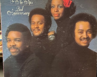 May include: A vinyl record cover featuring a group of three people, two men and one woman, with the text "Gladys Knight & The Pips 2nd Anniversary" in white lettering on a blue background.