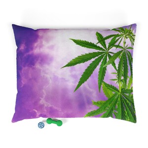 May include: A purple and white pillow with a green marijuana leaf design. The pillow is on a white background.