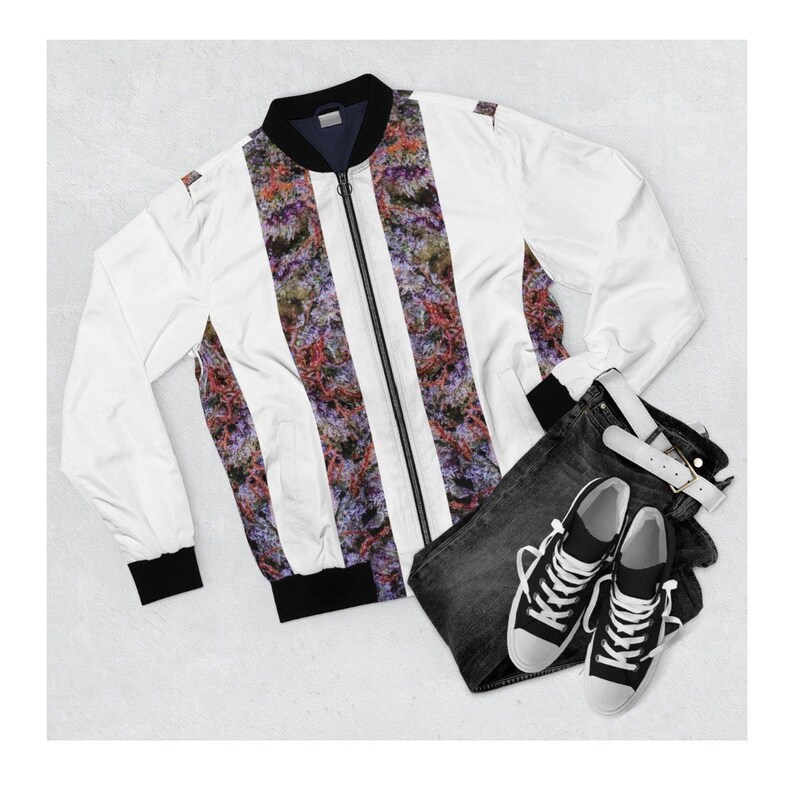 May include: A white bomber jacket with a zip fastening and black trim. The jacket features a colourful, abstract print. The jacket is paired with black jeans and white trainers.