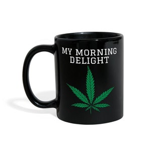 May include: Black ceramic coffee mug with a white graphic of a marijuana leaf and the text "MY MORNING DELIGHT".