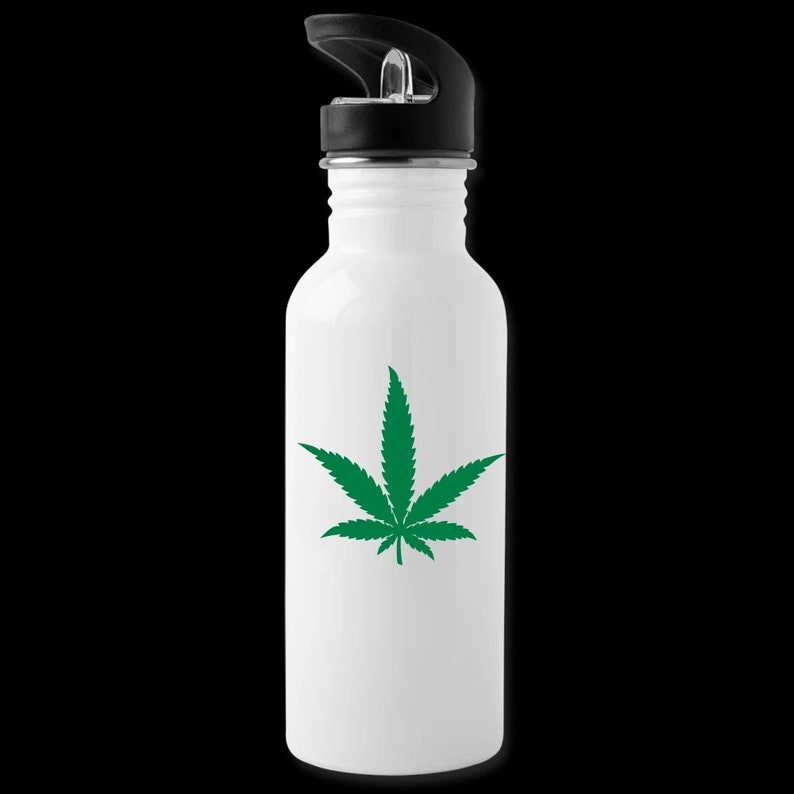 Puede incluir: Botella de agua de acero inoxidable blanca con un dise&ntilde;o de hoja de marihuana verde. La botella tiene una tapa de rosca negra con una tapa abatible.