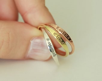 May include: Three thin gold rings with the names "Lorella", "Elena", and "Samantha" engraved on them.