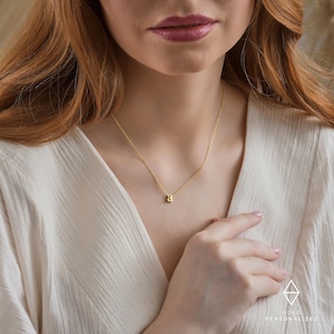 May include: A gold chain necklace with a small, gold letter 'A' pendant.