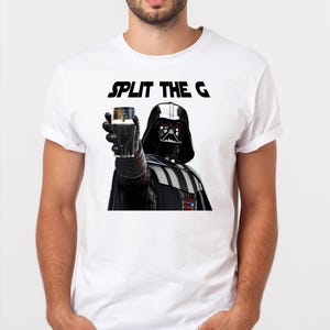May include: A white t-shirt with a black graphic of Darth Vader holding a glass of Guinness with the text "SPLIT THE G" above him.