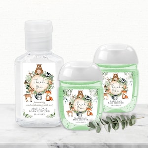 Könnte beinhalten: Drei durchsichtige Plastikflaschen mit Handdesinfektionsmittel mit Etiketten im Waldtier-Motiv. Die Etiketten haben einen grünen Hintergrund mit einem braunen Kreis in der Mitte, auf dem "Danke" steht. Die Etiketten zeigen außerdem einen Bären, einen Fuchs, ein Reh, einen Waschbären und eine Eule. Die Etiketten zeigen den Text "Matildas Babyparty" und das Datum "10.10.20XX".