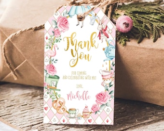 May include: White thank you tag with a pink and gold Alice in Wonderland theme. The tag features a floral wreath with a flamingo, a teapot, a Mad Hatter's hat, and a white rabbit. The text reads "Thank You" in gold lettering and "For coming and celebrating with me! Love, Michelle".