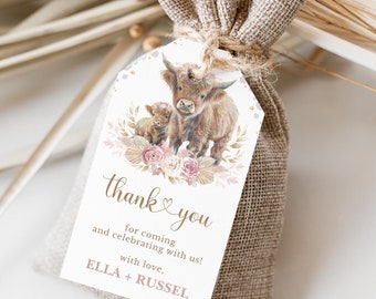 May include: A white thank you tag with a watercolour illustration of a brown and white highland cow and calf. The tag has gold glitter accents and pink flowers. The text on the tag reads "thank you for coming and celebrating with us! with love, ELLA + RUSSEL".