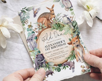 May include: A watercolor invitation for a first birthday party with a wild one theme. The invitation features a variety of Australian animals, including a koala, a kangaroo, a dingo, and a platypus. The text on the invitation reads "Wild One" and "Alexander's 1st Birthday".