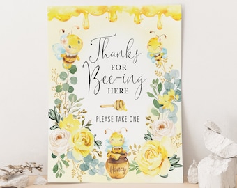 May include: A yellow and white printable sign with a bee theme. The sign says "Thanks for Bee-ing Here" and has a bee with a honey pot. The sign says "Please take one".