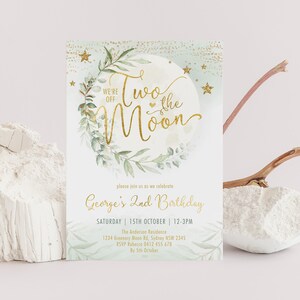 May include: A light blue and gold birthday invitation with a moon and stars design. The text reads "We're off to the moon" and "George's 2nd Birthday".