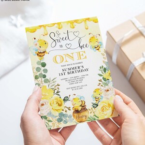 K&ouml;nnte beinhalten: Eine gelbe und wei&szlig;e Einladungskarte mit Bienen-Motiv. Die Karte sagt "So sweet to bee one" und hat einen Honigtopf mit einer Biene darauf. Der Text auf der Karte lautet "Bitte feiern Sie mit uns den 1. Geburtstag von Summer".