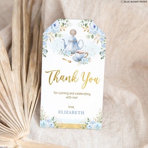 May include: A blue and gold thank you tag with a watercolor illustration of a teapot and teacup. The text reads "Thank You for coming and celebrating with me! love, ELIZABETH".