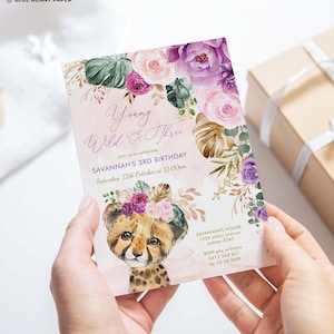Op de afbeelding: Een roze en paarse bloemen-verjaardagsuitnodiging met een cheeta-welpje dat een bloemenkrans draagt. De uitnodiging zegt "Young Wild & Three" en bevat de tekst "Savannah's 3rd Birthday, Saturday, 12th October at 12:00pm".