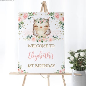 May include: Welcome to Elizabeth's 1st Birthday sign with a cute owl wearing a floral crown and surrounded by pink flowers and gold glitter.
