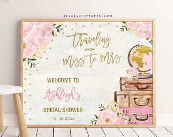 Op de afbeelding: Een welkomstbord voor een bruidsdouche met een reisthema. Het bord is roze en goud met een kaart achtergrond, bloemmotieven en een wereldbol. De tekst luidt "Traveling from Miss to Mrs. Welcome to Ashleigh's Bridal Shower 10.05.20XX".
