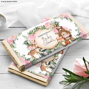 May include: White chocolate bar wrapper with a pink and green floral design. The wrapper features a deer, raccoon, fox, and bear surrounded by flowers. The text "Samantha's Baby Shower" is printed on the wrapper.