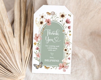 May include: A white thank you tag with a green archway and floral border. The text reads "Thank You" with a heart symbol and "for coming and celebrating with me! love, DELPHINE".