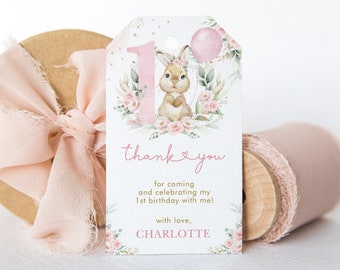 Può includere: Etichetta di ringraziamento rosa e verde con un coniglietto che tiene un palloncino rosa. L'etichetta dice "grazie" con un cuore e "per essere venuto a festeggiare il mio 1° compleanno con me! con amore, CHARLOTTE".