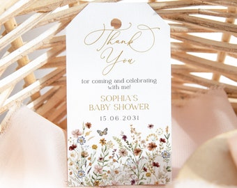 Puede incluir: Una etiqueta de agradecimiento blanca con letras doradas que dice "Gracias" por venir y celebrar conmigo! Baby Shower de Sophia 15.06.2031. La etiqueta tiene un diseño floral con mariposas.