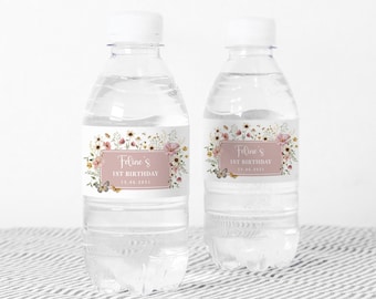 May include: Two clear plastic water bottles with personalized labels. The labels feature a floral design with butterflies and the text "Feline's 1st Birthday 13.06.2021".