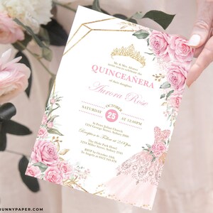 May include: A pink and gold Quincea&ntilde;era invitation with a floral design. The invitation features a crown, a pink dress, and the text "Quincea&ntilde;era" and "Aurora Rose".