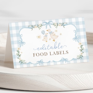 Puede incluir: Una tarjeta de etiqueta de comida plegada con un borde de patrón de cuadros vichy azul claro. La tarjeta presenta una ilustración de acuarela de gansos y las palabras "editable FOOD LABELS" en una fuente de escritura. Acentos florales y lazos completan el diseño.