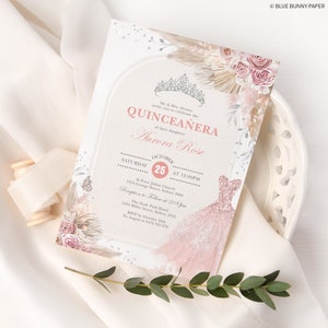 May include: A Quincea&ntilde;era invitation with a pink and gold color scheme. The invitation features a watercolor illustration of a dress, flowers, and a crown. The text on the invitation reads "Mr. & Mrs. Alvarez invite you to celebrate the Quincea&ntilde;era of their daughter Aurora Rose. Saturday, October 25th at 12:00 PM. St. Peter Julian Church, 1234 George Street, Sydney 2000. Reception to follow at 2:00 PM. The Hyde Park Hotel, 1234 Miller Street, Sydney 2345. RSVP by October 10th to Angela at 9412 345 678."
