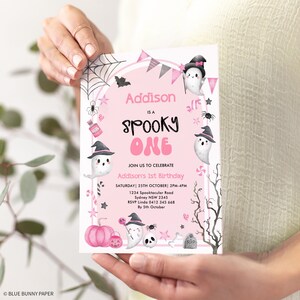 May include: Pink and white Halloween-themed first birthday party invitation with a ghost, a witch's hat, and a pumpkin. The invitation says "Addison is a Spooky One" and includes the date, time, and location of the party.
