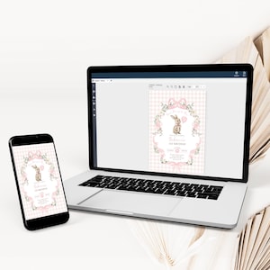 Op de afbeelding: Een laptop en smartphone tonen een digitale uitnodiging met een konijnenillustratie. De uitnodiging heeft een roze ruitjesachtergrond, bloemaccenten en de tekst "1e verjaardag". De apparaten staan op een wit oppervlak.