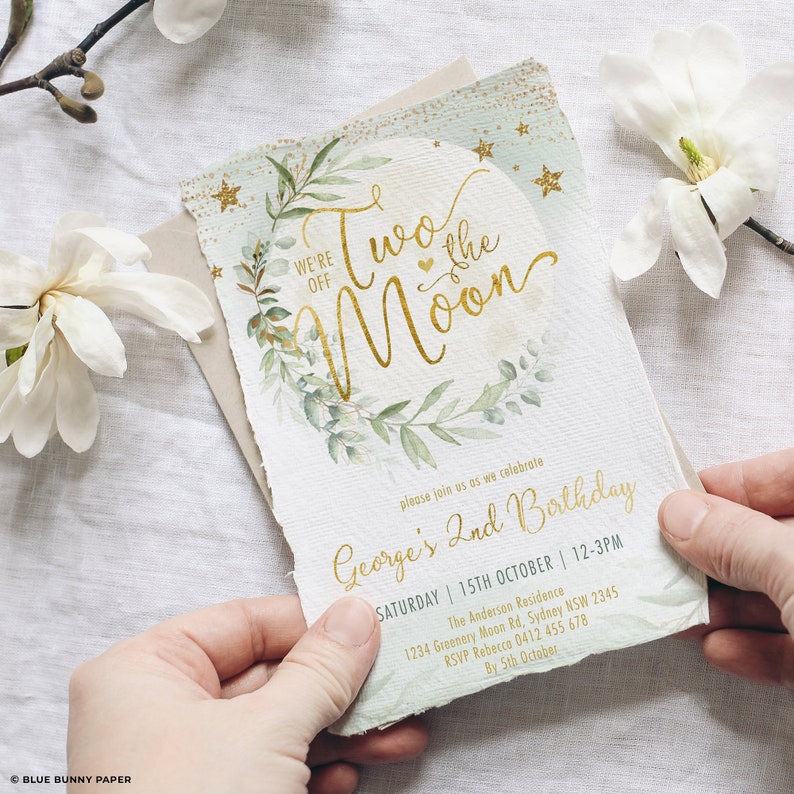 May include: A green and gold invitation card with a watercolor illustration of a moon and greenery. The text reads "We're off to the moon" and "George's 2nd Birthday". The invitation includes the date, time, and location of the party.