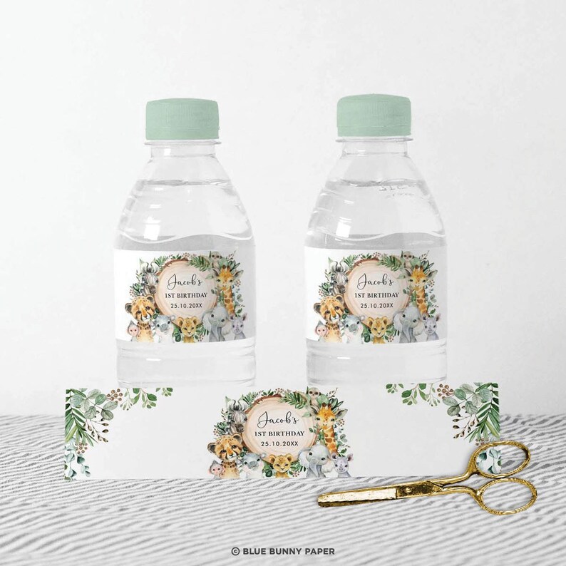 May include: Water bottle labels with a jungle animal theme. The labels feature a wreath of green leaves and a circle with the text "Jacob's 1st Birthday 25.10.20XX". There are illustrations of a lion, giraffe, elephant, monkey, and zebra.