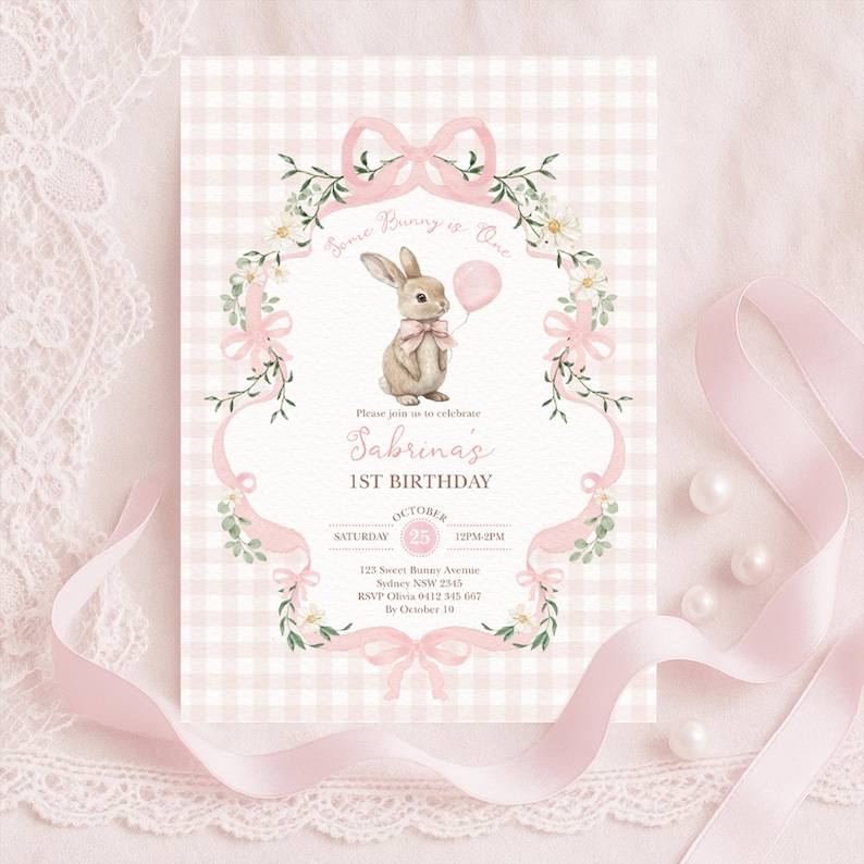 Op de afbeelding: Een roze en witte ruitvormige verjaardagsuitnodiging met een aquarel illustratie van een konijn met een roze ballon. De uitnodiging bevat de tekst "Some Bunny is One" en details voor Sabrina's 1e verjaardag.