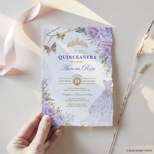 Pode incluir: Convite para uma Quincea&ntilde;era de cor roxa e dourada com um design floral e uma coroa. O convite inclui a data, a hora e o local do evento. Tamb&eacute;m inclui o nome da pessoa que est&aacute; sendo celebrada, Aurora Rose.