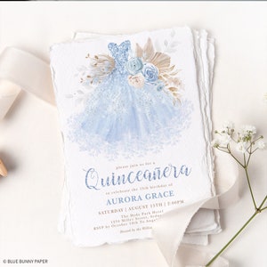 May include: A blue and white Quincea&ntilde;era invitation with a watercolor illustration of a blue sparkly dress with flowers. The text reads "Please join us for a Quincea&ntilde;era to celebrate the 15th birthday of Aurora Grace. Saturday, August 15th, 2:00 PM. The Hyde Park Hotel, 1234 Miller Street, Sydney. RSVP by October 10th to Angel. Hosted by the Williams."