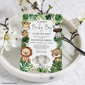 May include: A baby shower invitation with a jungle theme. The invitation features a green, white, and brown color scheme with illustrations of a giraffe, zebra, lion, elephant, and leopard. The text on the invitation reads "A Sweet Baby Boy Is On His Way!" and includes the name "Savannah Green" and the date and time of the shower.