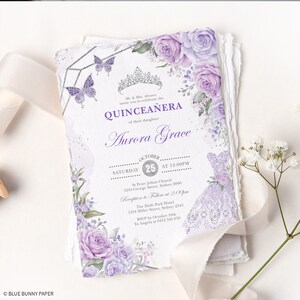 May include: Purple and silver Quincea&ntilde;era invitation with floral details, a crown, and butterflies. The invitation includes the date, time, and location of the event. It also includes the name of the celebrant, Aurora Grace.