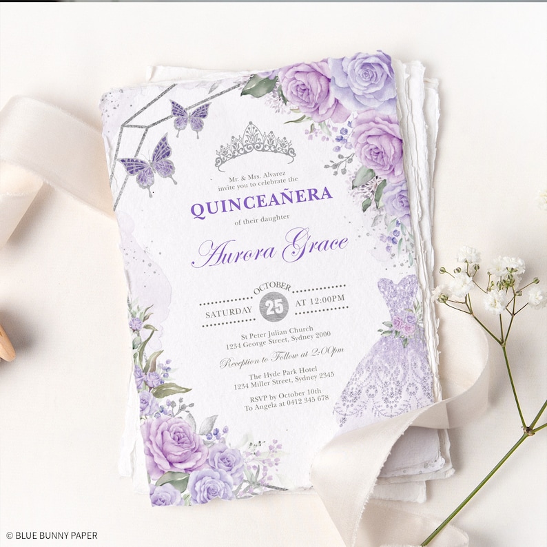 May include: Purple and silver Quincea&ntilde;era invitation with floral details, a crown, and butterflies. The invitation includes the date, time, and location of the event. It also includes the name of the celebrant, Aurora Grace.
