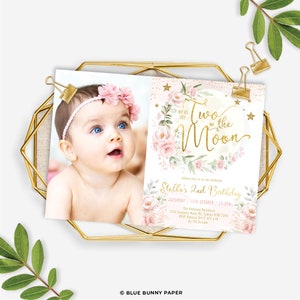 May include: A pink and gold birthday invitation with a photo of a baby girl. The invitation says "We're off to the moon" and features a moon with pink flowers and gold stars. The text also includes the details of the birthday party, including the date, time, and location.