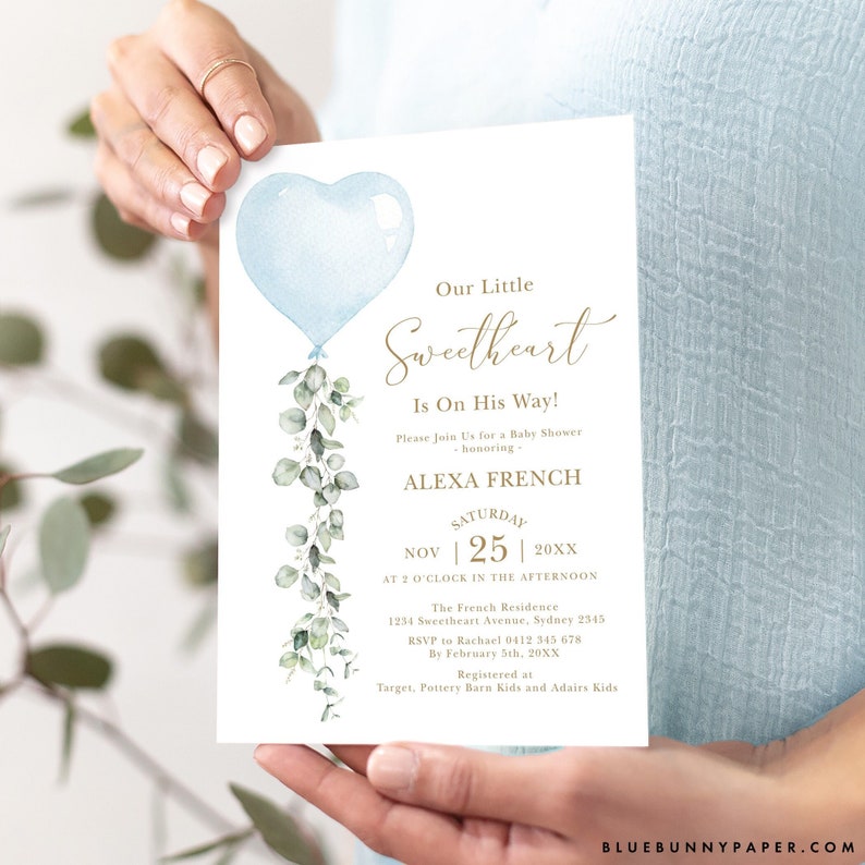 May include: A blue and green baby shower invitation with a heart-shaped balloon and eucalyptus leaves. The text reads "Our Little Sweetheart Is On His Way!" and includes the date, time, and location of the event.  RSVP information and registry details are also included.