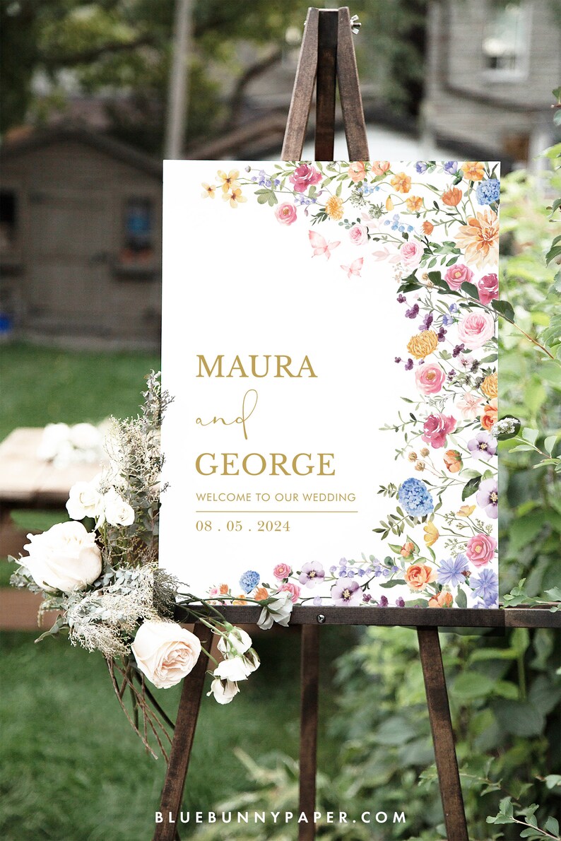 Pode incluir: Um cartaz de casamento branco com uma borda floral. O cartaz diz "Maura e George, Bem-vindos ao nosso casamento, 08.05.2024".
