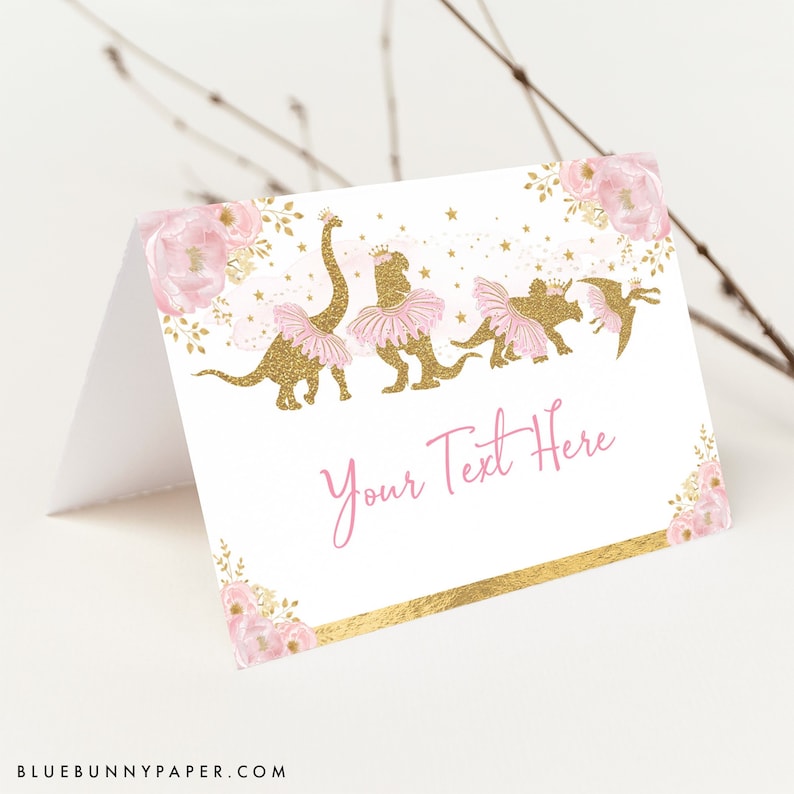 Puede incluir: Tarjeta de lugar imprimible rosa y dorada con un dise&ntilde;o floral y una l&iacute;nea de dinosaurios con tut&uacute;s. El texto "Your Text Here" est&aacute; impreso en la tarjeta.