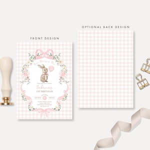 Op de afbeelding: Een uitnodiging voor de eerste verjaardag van een baby met een roze ruitjespatroon en een konijnenillustratie. De tekst luidt "Sabrina's 1e verjaardag". Een lakzegel, twee gouden paperclips en een lint zijn ook zichtbaar.