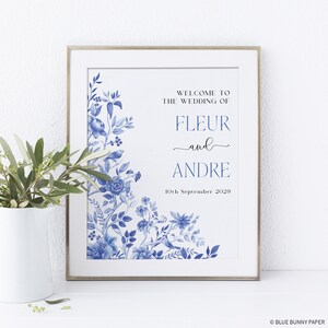 May include: A wedding announcement sign with blue and white floral designs. The text reads "Welcome to the wedding of Fleur and Andre, 10th September 2029".