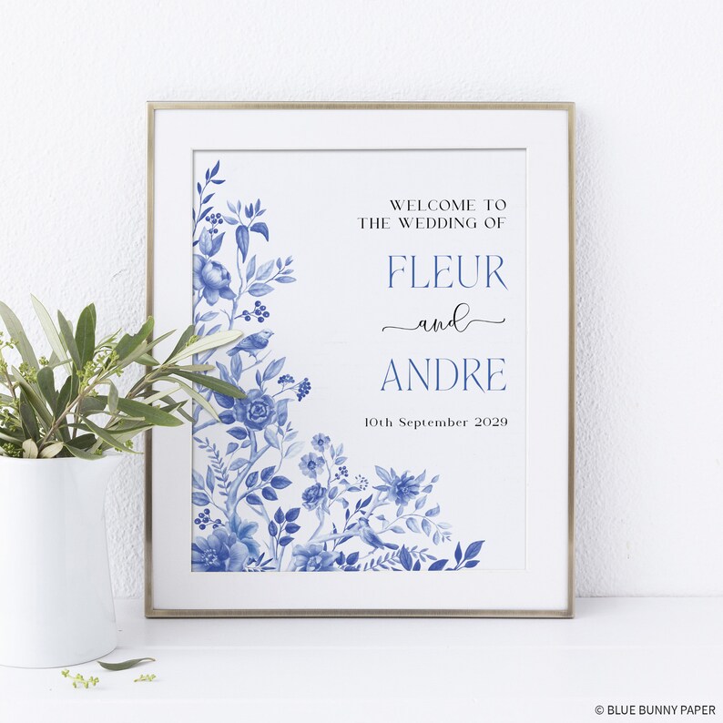 May include: A wedding announcement sign with blue and white floral designs. The text reads "Welcome to the wedding of Fleur and Andre, 10th September 2029".