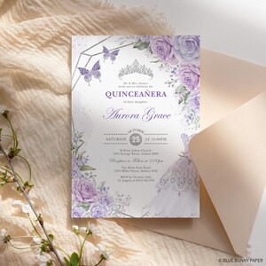 May include: A Quincea&ntilde;era invitation with a silver glitter background and purple watercolor flowers. The text reads "Mr. & Mrs. Alvarez invite you to celebrate the Quincea&ntilde;era of their daughter Aurora Grace." The date is October 25th at 12:00 PM. The invitation includes the location of the church and reception.