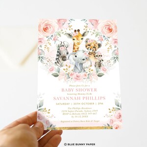 May include: A pink and gold baby shower invitation featuring a floral wreath and a group of safari animals including a giraffe, zebra, elephant, and cheetah. The text on the invitation reads "Please Join Us for a Baby Shower honouring Mommy-To-Be SAVANNAH PHILLIPS SATURDAY 30TH OCTOBER | 3PM The Phillips Residence 1234 Safari Parade, Sydney 2345 RSVP to Belinda 0412 345 667 by 10.12.20XX Registered at Pottery Barn Kids & Target BLUE BUNNY PAPER"